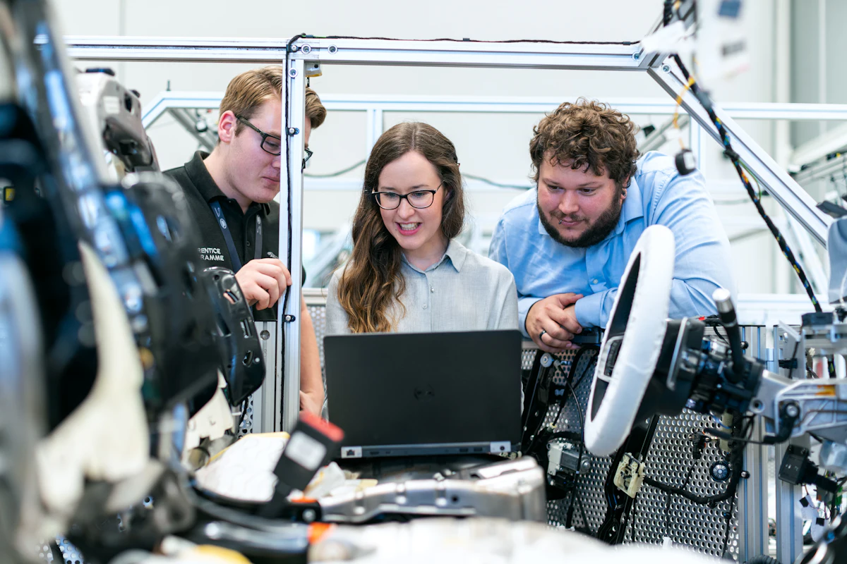 Drei Kollegen aus der Technik schauen gemeinsam auf einen Laptop